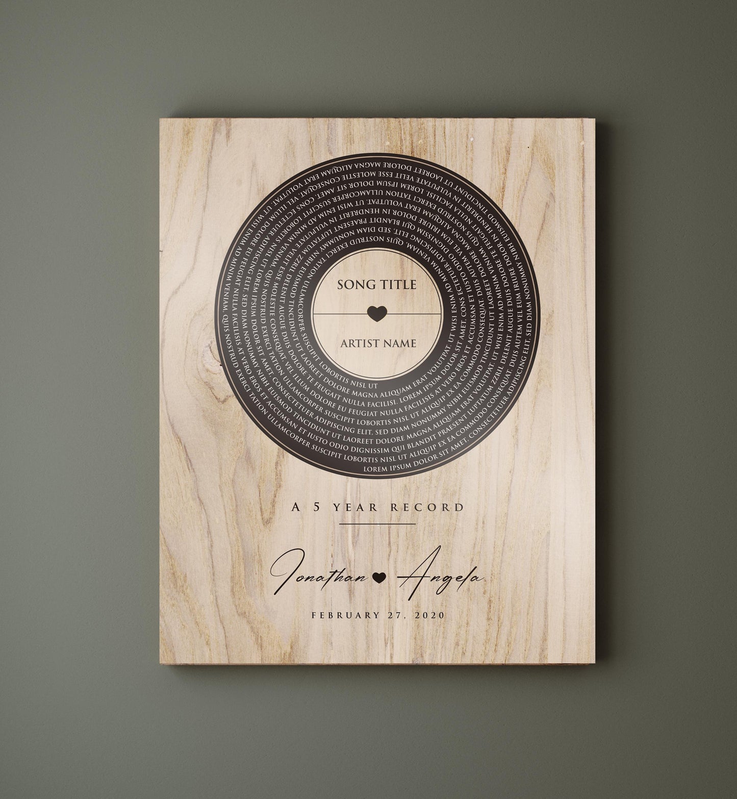 This is a photo of a 5th wedding anniversary, Our 5 Year Record wall plaque is a wood plaque - The record design pops in a deep coffee tone set against a natural polished birch - featuring song lyrics of choice in a vinyl record motif, accented with the couple's names with a heart symbol between then and the couples wedding date