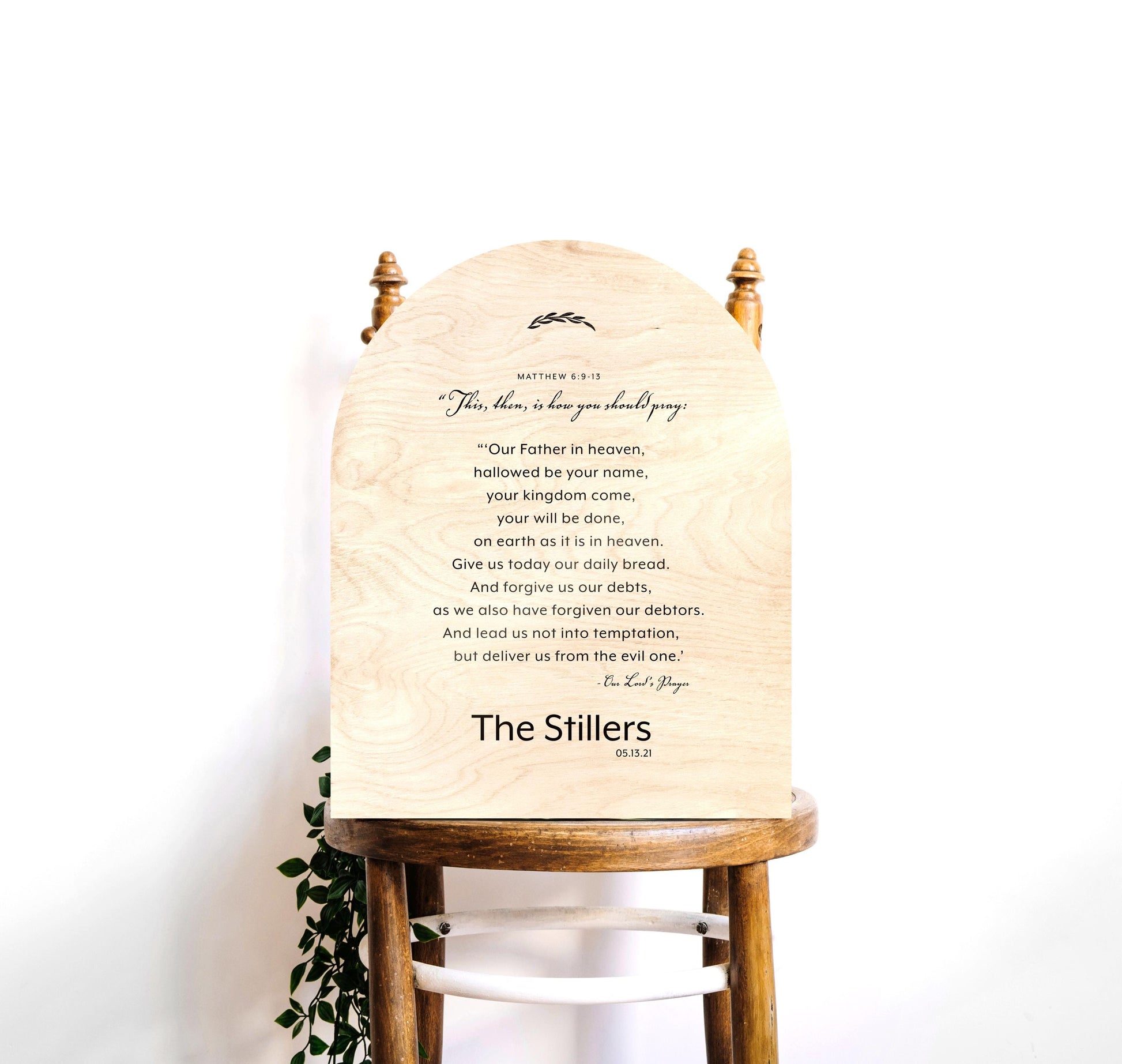 Wood arched The Lord's Prayer Plaque and Family Name sign, Verses of Matthew 6:9-13 are centered in stanza format with a family name "Thompson" beneath. A decorative botanical motif accents the top of the plaque.