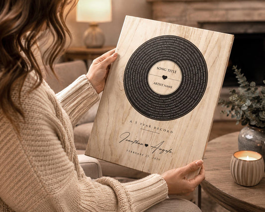 Attractive woman holds a wooden vinyl record plaque with custom song lyrics or wording spiraling around a label motif in the center, with names and a date at the bottom. of the plaque, and the phrase 5 year record, to commemorate the 5th anniversary.